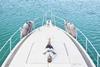 smiling-man-lying-on-deck-of-his-motor-yacht-using-2024-09-16-00-58-51-utc