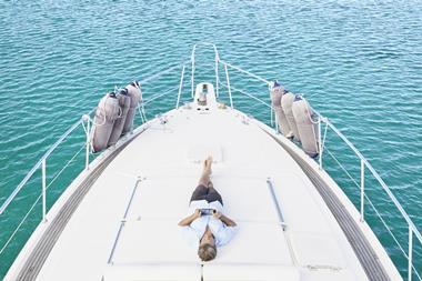 smiling-man-lying-on-deck-of-his-motor-yacht-using-2024-09-16-00-58-51-utc