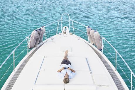 smiling-man-lying-on-deck-of-his-motor-yacht-using-2024-09-16-00-58-51-utc